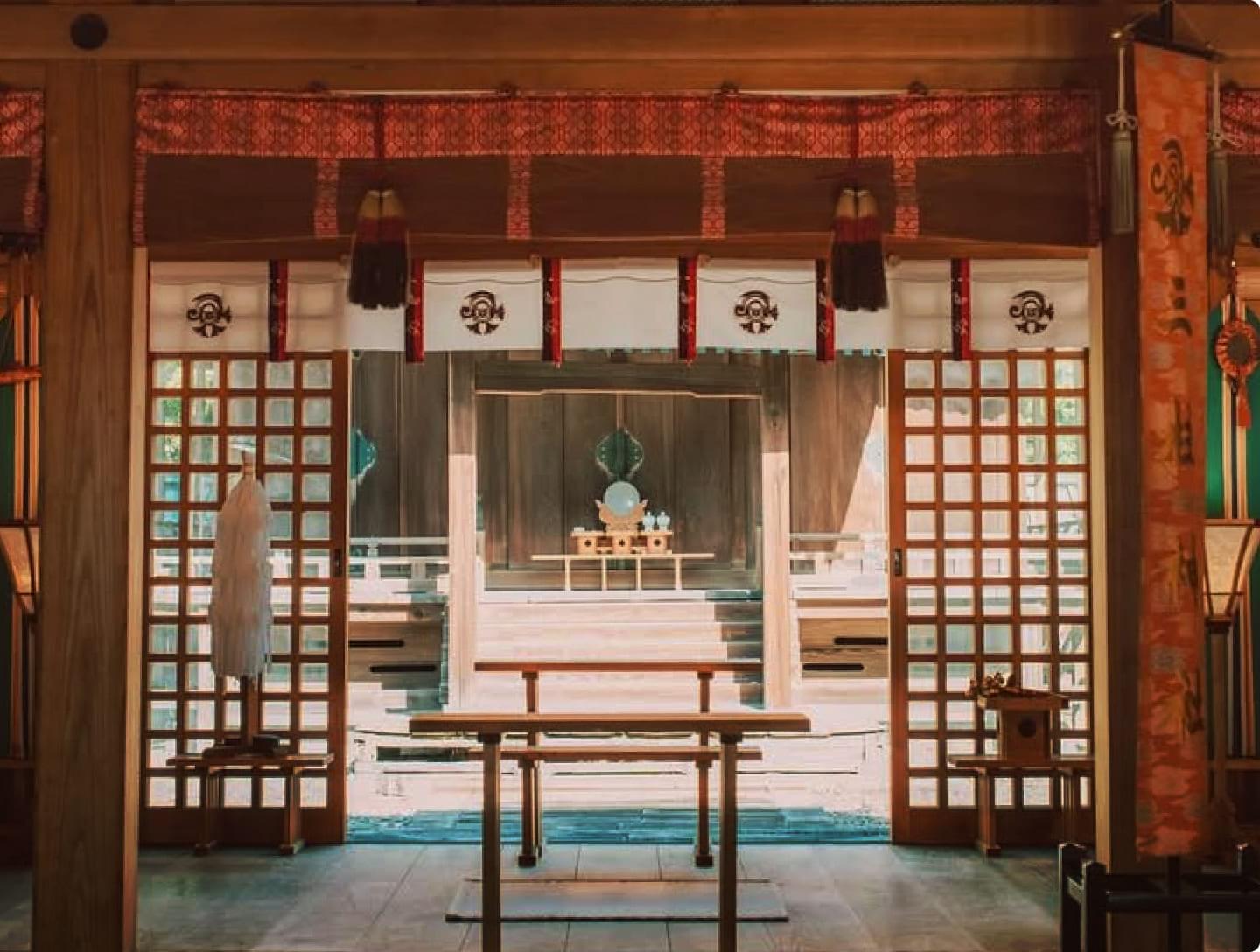 The interior of the Yanagawa Shrine. The stately main hall features vermilion-decorated transoms, lattice windows, and a plain wooden altar housing the deity.